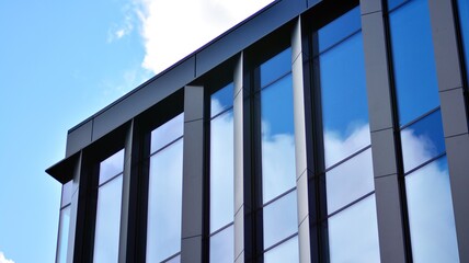 Obraz premium Modern office building detail, glass surface on a clear sky background. Transparent glass wall of office building. 