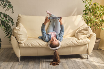 Child playing on ipad tablet pc on the sofa at home