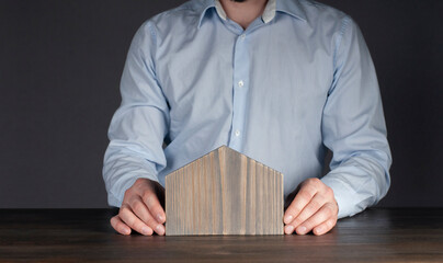 Male businessman in a shirt. Holds a miniature model of the house. Little house. Concept of...