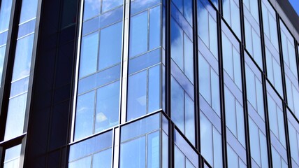 Obraz premium Modern office building detail, glass surface on a clear sky background. Transparent glass wall of office building. 