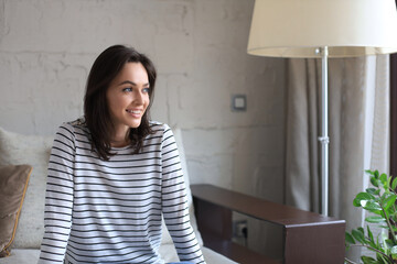 Beautiful young woman sitting on sofa, indoors.