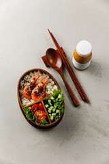 Bento wooden lunch box with rice, shrimp and vegetable salad on grey table background