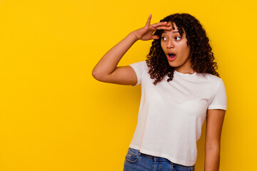 Young mixed race woman isolated on yellow background looking far away keeping hand on forehead.