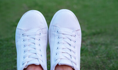 Close up white sports sneakers on a green grass background, blank copy space selective focus