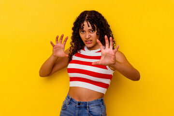 Young mixed race woman isolated on yellow background upset screaming with tense hands.