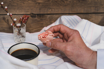 Fototapeta na wymiar Bitten macaroon cake in hand. Breakfast concept in bed