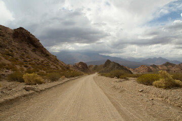 Dirt road into nowhere. Traveling along the arid desert route in the rocky mountains.	