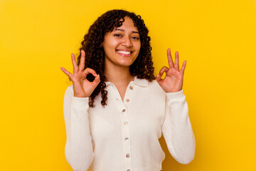 Young mixed race woman isolated on yellow background cheerful and confident showing ok gesture.