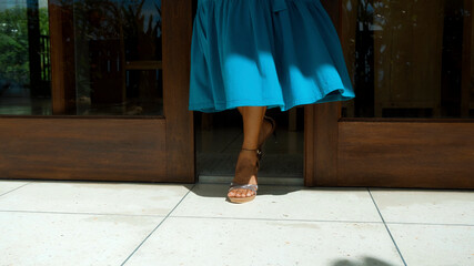 legs of a young girl in a blue dress leaving the house in shoes opening wooden doors