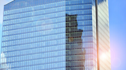 Modern office building detail, glass surface on a clear sky background. Transparent glass wall of office building.  