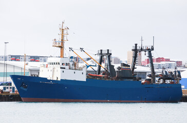 Naklejka premium Industrial trawler ship with blue hull stands moored