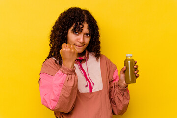 Young mixed race sport woman holding a smoothie isolated on yellow background