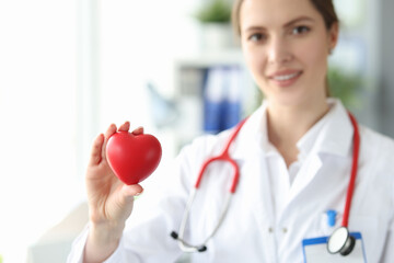 Woman cardiologist holds small red heart in her hand