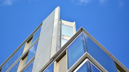 Obraz premium Modern office building detail, glass surface on a clear sky background. Transparent glass wall of office building. 