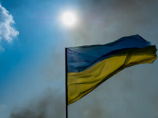 Scattered Ukraine flag in smoke and blue sky