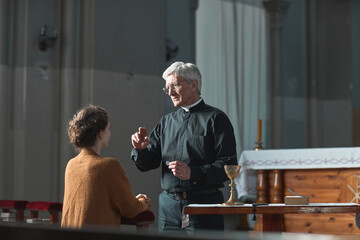 Senior priest blessing the faithful woman in the church