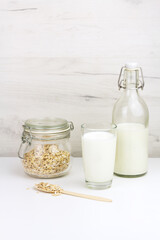 Dairy free oat milk and flakes in a glass jar on light background