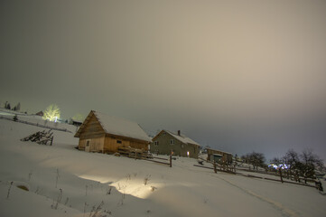 Small wooden house in the Carpathians, on the background of the winter forest at night