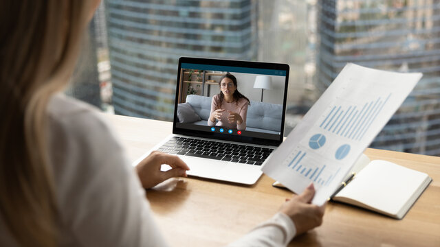 Back close up view of female employee have online video consultation with coach on laptop. Business colleagues or partners talk on webcam zoom digital call on computer. Virtual event concept.