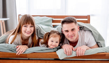 Family under the blanket in the bed