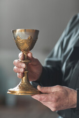 Close-up of priest holding the cup with wine while standing in the church