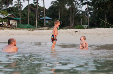 two children: toddler boy and baby girl on a sandy beach