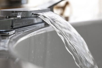 Spout running water from wide bath tube faucet into a hot  Jacuzzi.