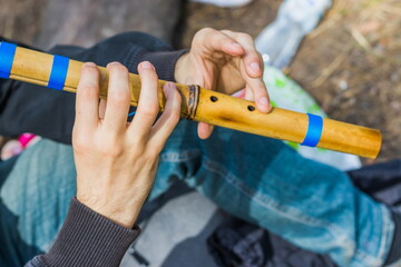 Man playing bamboo flute musical instrument Pimak. Hands and flute of a man playing the flute.