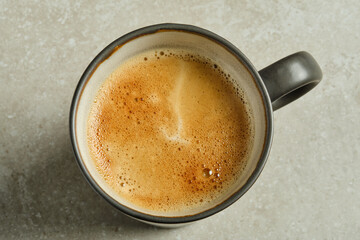 Cup of coffee on grey background, top view.