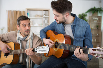 Obraz premium mid adult man teaches guitar to a male student