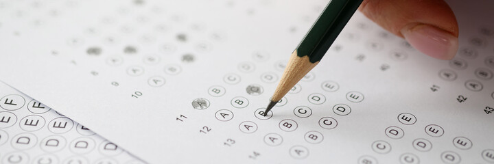 Woman solving tests and writing in pencil on paper closeup