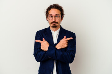 Young business man isolated on white background points sideways, is trying to choose between two options.