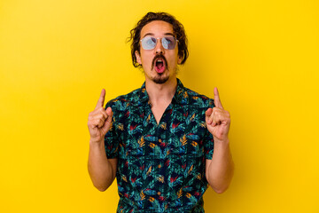 Young caucasian man wearing summer clothes isolated on yellow background pointing upside with opened mouth.