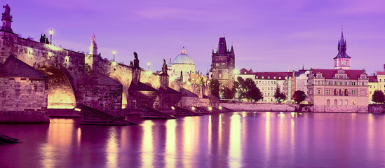 Romantic Charles Bridge in Prague, purple banner. Romantic Prague. Panoramic travel cityscape. Illuminated Charles Bridge reflected in Vltava river at night.