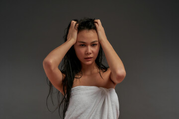 Young beautiful asian half naked woman tousled her hair in bath towel 