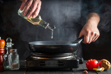 Chef or cook adds olive oil to the pan while cooking. Working environment on restaurant kitchen