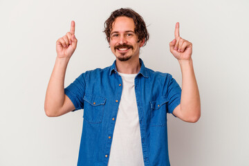 Young caucasian man isolated on white background indicates with both fore fingers up showing a...