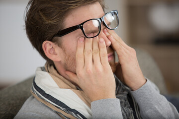 man wearing eyeglasses rubbing his eyes