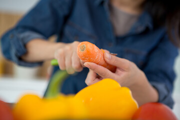 cropped image of woman peeling a carrot