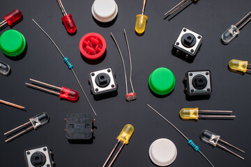 Colored LEDs, pushbutton switches , resistors and light sensor on a black background