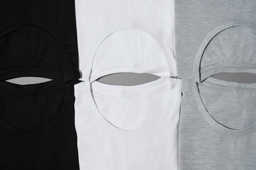 Flat lay of folded monochrome t shirts gray, black and white isolated on gray surface