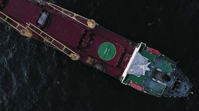 Aerial zoom in view bulk carrier in open sea. Vessel with dry freight, agricultural crops or coal transportation. Top container ship deck in ocean. Concept of shipping, logistics and seaborne trade