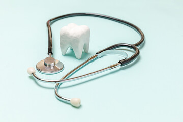 Health dental care concept. Medicine equipment stethoscope white healthy tooth isolated on pastel blue background. Instrument device for dentist doctor. Dental oral hygiene, dentist day.