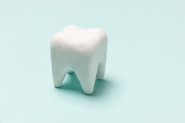 Health dental care concept. White healthy tooth model isolated on pastel blue background. Teeth whitening, dental oral hygiene, teeth restoration, dentist day. Copy space.