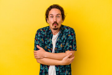 Young caucasian man isolated on yellow background shrugs shoulders and open eyes confused.