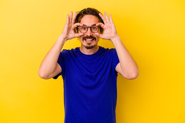 Naklejka premium Young caucasian man isolated on yellow background showing okay sign over eyes