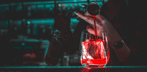 Closeup shot of bartender hand making negroni cocktail. Negroni classic cocktail and gin short...
