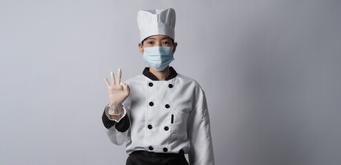 Chef wearing face protective medical mask or respirator for protection from virus disease. Food safety and coronavirus pandemic. chef posing gesture represent online ordering. food healthcare.