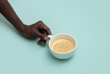 Black female hand hold cup of coffee on blue background