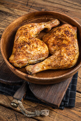 BBQ Grilled chicken legs in a wooden plate with herbs. wooden background. Top view